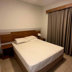 a bedroom with a large bed with white sheets at Ilhas do Lago Eco Resort in Caldas Novas