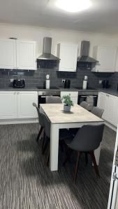a kitchen with a table and chairs and white cabinets at Whole property in Kirkcaldy Fife in Fife +14 photos