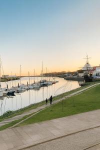 two people walking a dog near a marina with boats at Naval - Marina View Apartments in Vila do Conde