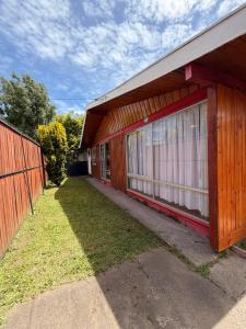 a red building with a fence next to a yard at Casa Cypresses in Temuco