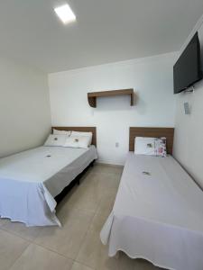 two beds in a room with a tv on the wall at WT Corais Flats in Maragogi