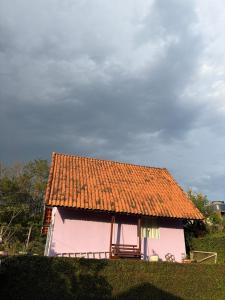 a pink house with an orange roof on a field at Marcos Araújo in Mairinque