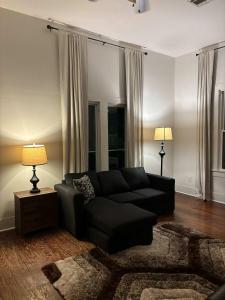 ein Wohnzimmer mit einer schwarzen Couch und zwei Lampen in der Unterkunft Modern Cajun Retreat Near Downtown in Lafayette