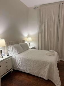 ein weißes Schlafzimmer mit einem Bett und einem Fenster in der Unterkunft Modern Cajun Retreat Near Downtown in Lafayette