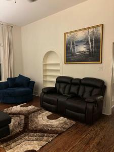 ein Wohnzimmer mit einem schwarzen Ledersofa und einem Teppich in der Unterkunft Modern Cajun Retreat Near Downtown in Lafayette