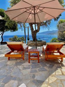deux chaises et un parasol sur une terrasse en pierre dans l'établissement Πέτρινη αυλή, Αρμενιστης Ικαρια, à Armenistis