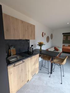 a kitchen with a sink and a table with chairs at Gîte l'Hortensia Rose in Guémar