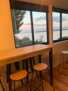 een tafel met krukken voor een groot raam bij Cabane front de mer in Saint-Brieuc