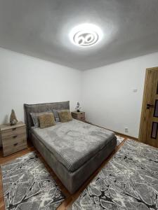a bedroom with a bed and a white wall at Apartament Central Ilie Balaci 15 in Craiova