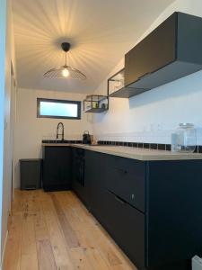 een keuken met zwarte kasten en een aanrecht bij Cabane front de mer in Saint-Brieuc