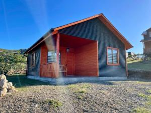a small wooden house with a red door at Cabaña Canelita in Cochrane +3 photos