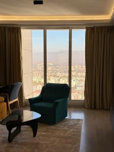 a living room with a green chair and a large window at A2I - 33rd Floor SkyCity Residence With Skopje View in Skopje