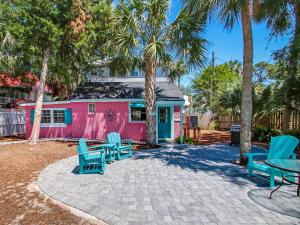 ein rosa Haus mit blauen Stühlen und Palmen in der Unterkunft Surf Puppy in Tybee Island
