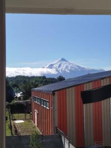 ein rotes Gebäude mit einem schneebedeckten Berg im Hintergrund in der Unterkunft Depto con vista al Volcán y piscina in Villarrica
