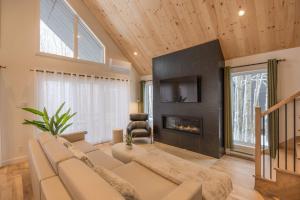 un soggiorno con divano e camino di Kos - Domaine du Grand Portneuf - Spa Nature & Comfort a Pont-Rouge