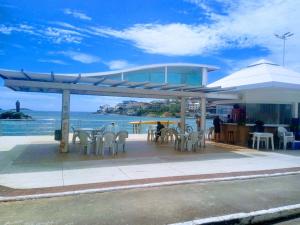 a pavilion with tables and chairs and the ocean at Beira-mar, vista e localização in Guarapari
