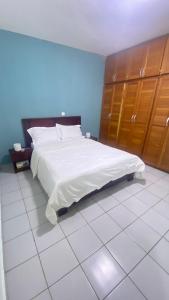 Schlafzimmer mit einem großen weißen Bett und Holzschränken in der Unterkunft Les Jardins Prives Odza in Jaunde