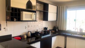 una cocina con electrodomésticos en blanco y negro y una ventana en Conforto Total - Do café ao Sabão tudo incluso, en Varginha 10 fotos más