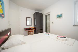 a bedroom with a large white bed and a table at Apartments Dvori Novalja in Novalja +61 photos