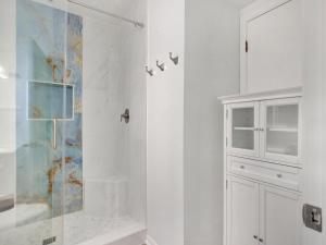 a white bathroom with a shower and a cabinet at Oceanview Bliss in Tybee Island +28 photos