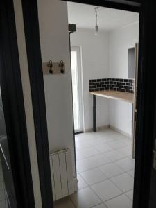 an open door to a kitchen with a white tile floor at Studio indépendant in Yvré-lʼÉvêque