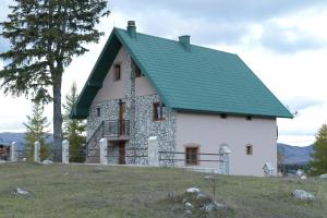 una casa blanca con techo verde en una colina en Apartmani pod Durmitorom, 