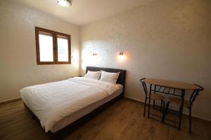 Un dormitorio con una cama y una mesa y una ventana. en Apartmani pod Durmitorom, 