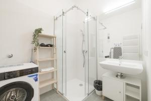 a bathroom with a shower and a sink and a washing machine at Cosy Penzing Vienna in Vienna +56 photos