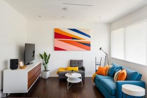 ein Wohnzimmer mit einem blauen Sofa und einem Gemälde in der Unterkunft Modern Venice Beach Stay - Walk to Marina & Boardwalk in Los Angeles