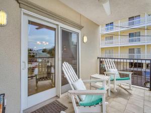 a patio with two chairs and a balcony at Silver Seas 103 in Tybee Island