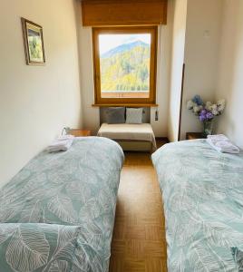 two beds in a room with a window at Casa DaRin in Vigo di Cadore