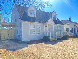 a white house with a porch and a fence at 508 A The Shore Break Cottage in Virginia Beach +16 photos
