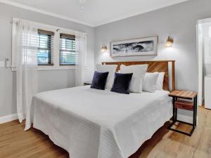 una camera bianca con un grande letto con cuscini blu di Ebb & Flow Apartment House a Tybee Island Altre 38 foto