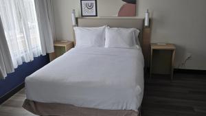 una camera da letto con un letto grande con lenzuola e cuscini bianchi di Spark By Hilton Wilmington a Wilmington
