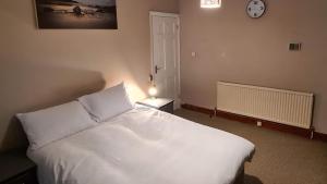 ein Schlafzimmer mit einem weißen Bett und einer Uhr an der Wand in der Unterkunft 1BR London Home Private Bathroom and Kitchen 10min to Heathrow in Cranford