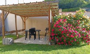 a table and chairs under a pergola with flowers at Terra Médiane in Serres-sur-Arget