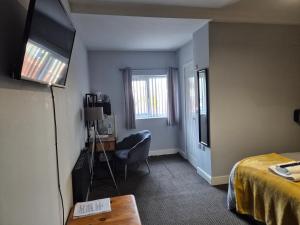 a room with a bed and a desk and a television at Rooms at number 4 in North Walsham