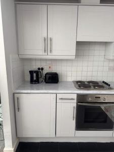 une cuisine avec des armoires blanches et un four à plaques de cuisson dans l'établissement 2 bedroom apartment Dublin 8, à Dublin