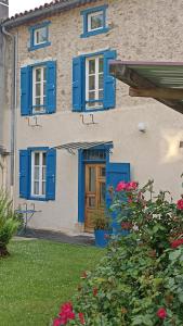 a house with blue shutters and flowers in front of it at Terra Médiane in Serres-sur-Arget