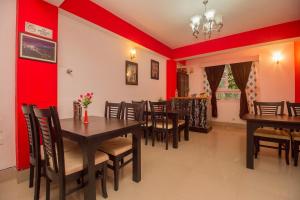 BhurtukHotel O Park Inn的一间拥有红色墙壁和木桌及椅子的用餐室