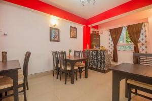 BhurtukHotel O Park Inn的一间拥有红色墙壁和木桌及椅子的用餐室