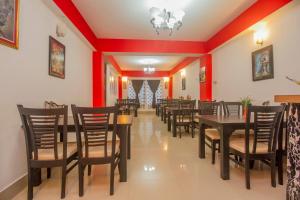 BhurtukHotel O Park Inn的一间拥有红色墙壁和木桌及椅子的用餐室