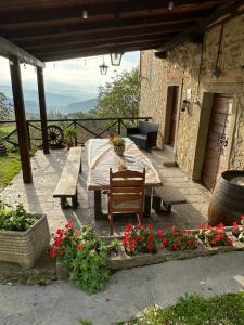une terrasse avec une table, des bancs et des fleurs dans l'établissement Casa Vacanze Il Puggio, à Capolona