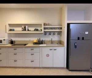 a kitchen with white cabinets and a refrigerator at מתחת לעץ התות בכפר in Bet Alfa +8 photos
