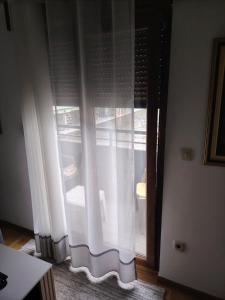 a window with white curtains in a room at Sicilija apartment in Podgorica