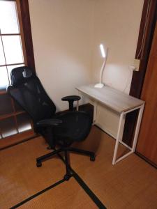 une chaise placée à côté d'un bureau avec une lampe dans l'établissement たけのこ古民家いちはらキッズベース, à Ichihara