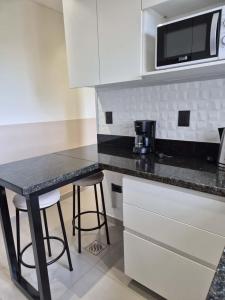 una cocina con mostrador, mesa y taburetes en Molas Tower 114B, en Asunción
