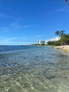 una spiaggia con acqua limpida, palme ed edifici di Modern 2BR Condo Near the Beach Juan Dolio a Villas del Mar