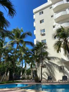 un edificio con palme accanto a una piscina di Modern 2BR Condo Near the Beach Juan Dolio a Villas del Mar
