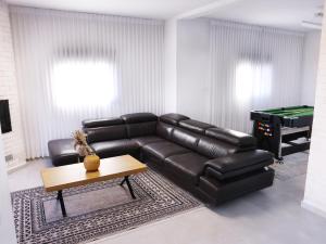 un salon avec un canapé en cuir et une table de billard dans l'établissement וילה Mandala אירוח&אירועים, 